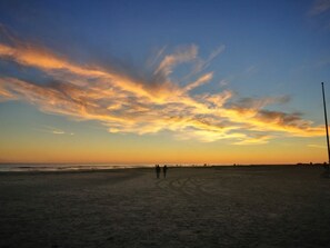 A beach with a clear sky and a few people walking. - "seahorse" House Clarinet (Nebel)