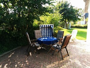 An outdoor seating area with a round table and four chairs, surrounded by lush greenery. - "seahorse" House Clarinet (Nebel)