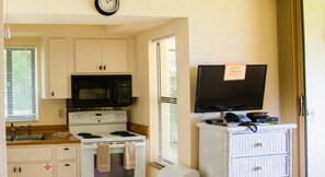Une petite cuisine équipée d’un four à micro-ondes, d’une cuisinière et d’un évier.