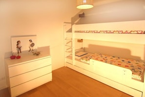 A child's bedroom with a bunk bed, a dresser, and a wall-mounted shelf with toys. - Apartment in Cadzand with swimming pool (Cadzand)