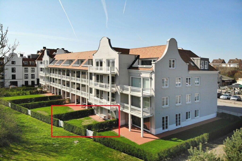 A multi-story building with balconies, a courtyard, and a parking area.