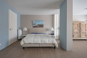 Ein Schlafzimmer mit einem Bett, Nachttischlampen, einem Bild an der Wand und einem Holzschrank.