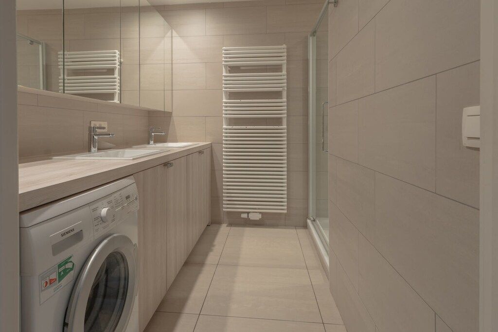 Un baño moderno con lavadora, lavamanos y toallero.