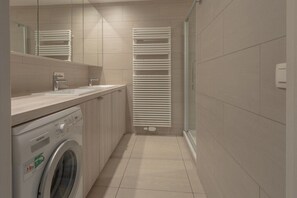 Een moderne badkamer met een wasmachine, een wastafel en een handdoekhouder.