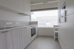 A kitchen with a built-in oven, a window, and a view of the outside. - Holiday apartment with 1 bedroom (Cadzand-Bad)