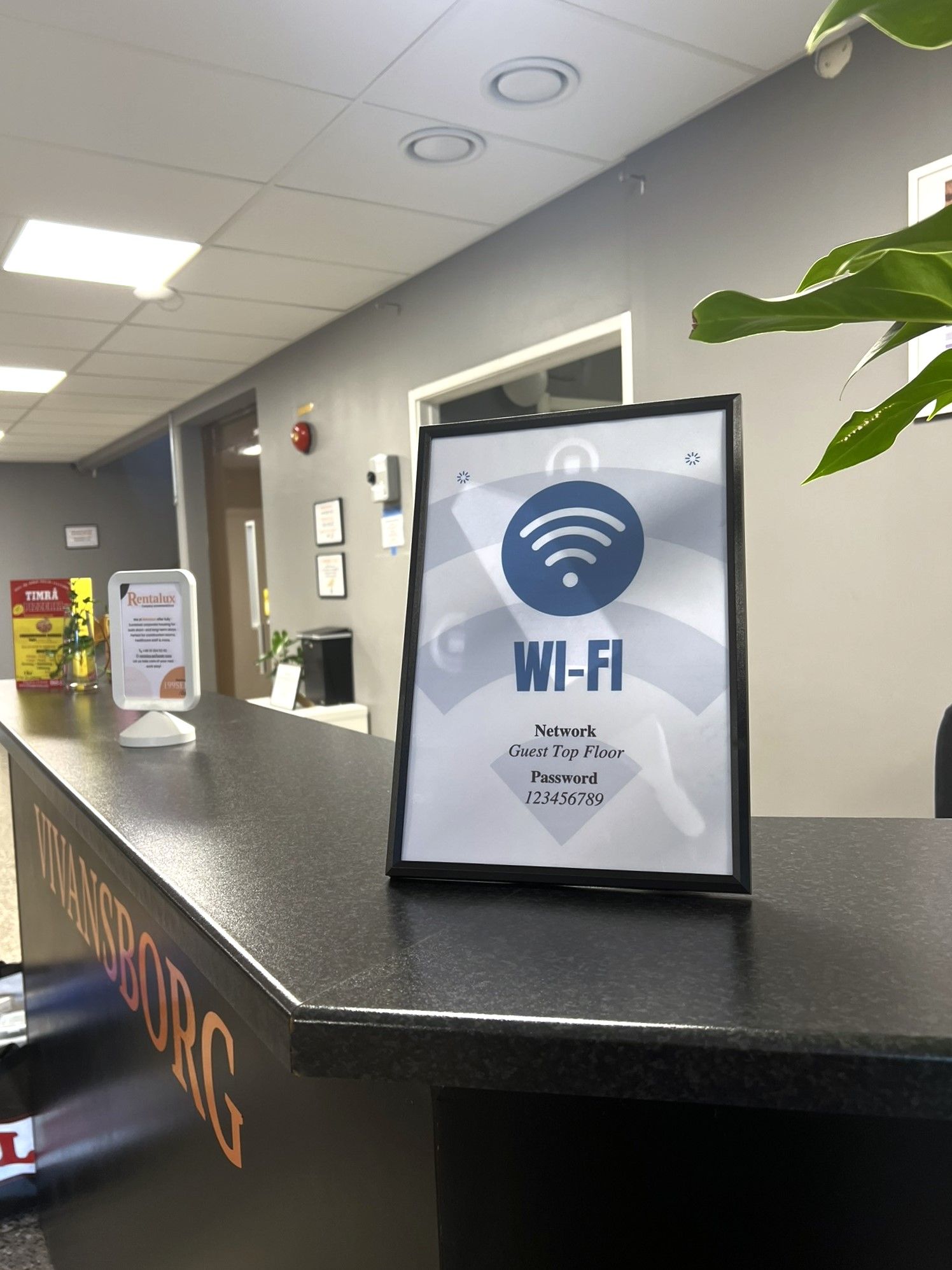 Una recepción con un cartel de Wi-Fi, la contraseña de la red para huéspedes en el piso superior y un letrero de Timra al fondo.