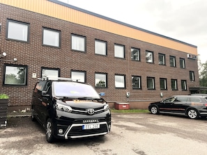 Un coche negro estacionado frente a un edificio de ladrillo de varios pisos, con varias ventanas y un cartel que dice 'Rentallux AB'.