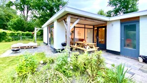Een modern huis met een overdekte patio, een houten terras en een tuin.