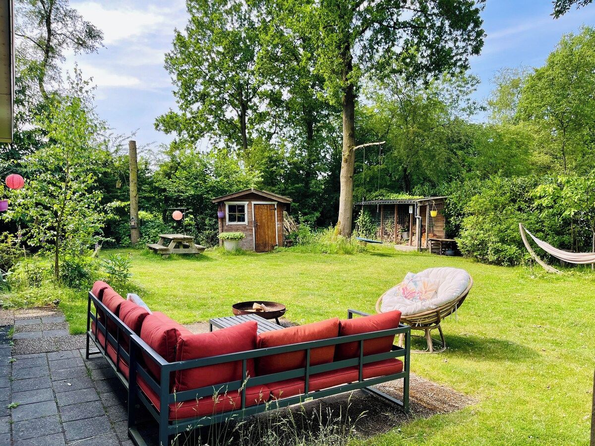 Un giardino con un divano rosso, un'amaca e una piccola costruzione in legno.