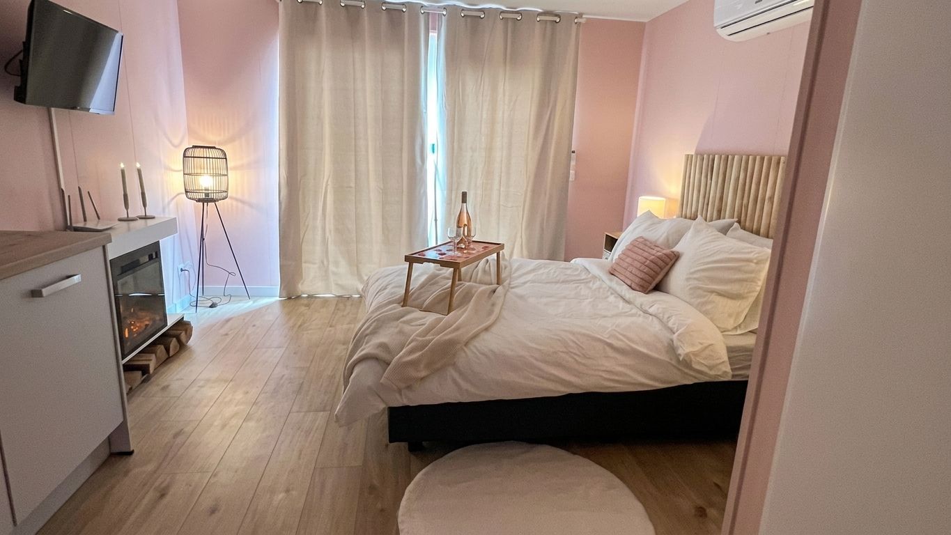 Ein Hotelzimmer mit Bett, Nachttisch, Lampe und einem an der Wand befestigten Fernseher.