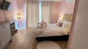 A hotel room with a bed, bedside table, lamp, and a TV mounted on the wall.