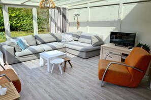 A modern outdoor living area with a sectional sofa, a television, and a small table. - Holiday home in Cadzand with barbecue (Cadzand)
