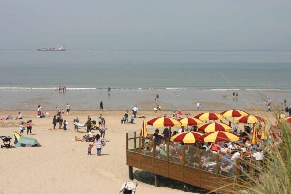 A beach with people, umbrellas, and a wooden structure.