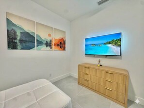 Une chambre avec un lit, un téléviseur fixé au mur et une armoire en bois.