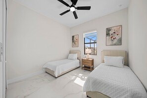 A bedroom with two beds, a ceiling fan, and artwork on the walls. - Canal Life-Private Pool-Tropical Florida Escape (Cape Coral)