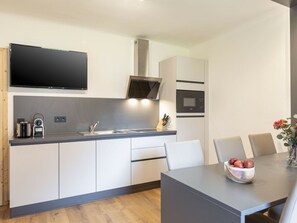 Una cucina moderna con forno integrato, microonde e televisore a schermo piatto.