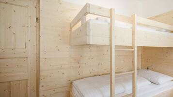 Een stapelbed met een ladder, een houten garderobe en een effen muur.
