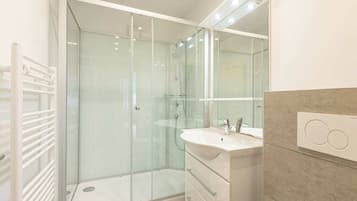 A modern bathroom with a glass-enclosed shower, a white vanity with a sink, and a large mirror.