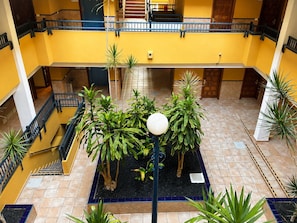 A multi-level atrium with a central garden area, multiple staircases, and a yellow and white color scheme.