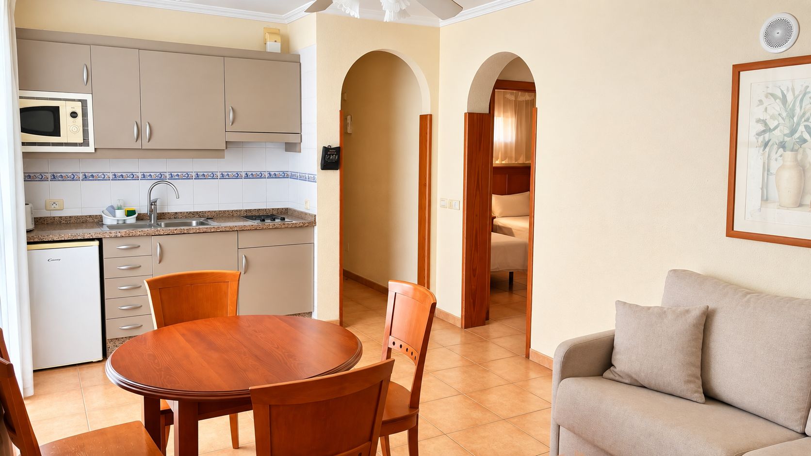 Un espacio habitable compacto con kitchenette, comedor y sofá.