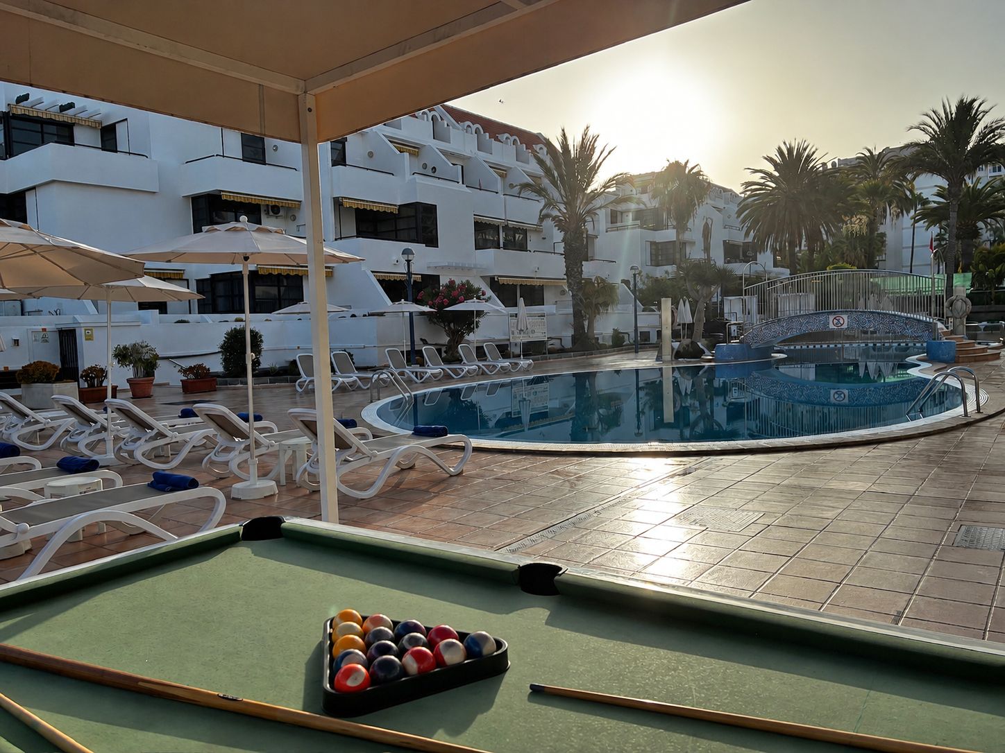 Un área de piscina con sillones de descanso y mesa de billar.