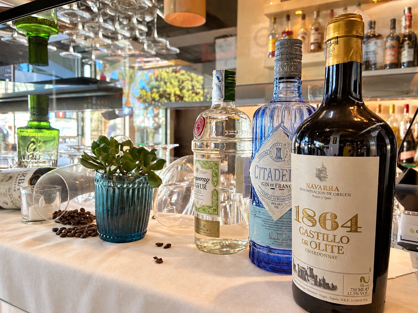 Zona de bar con diversas botellas de licor, incluyendo una destacada botella de vino Castillo de Olite 1864.