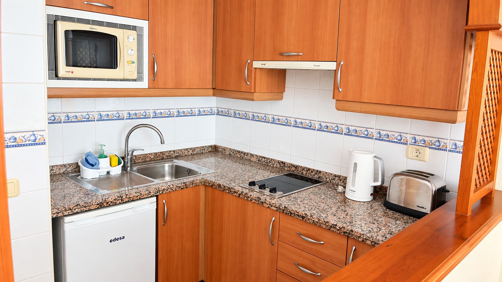 Una cocina compacta equipada con microondas, lavamanos, tostadora y cafetera.