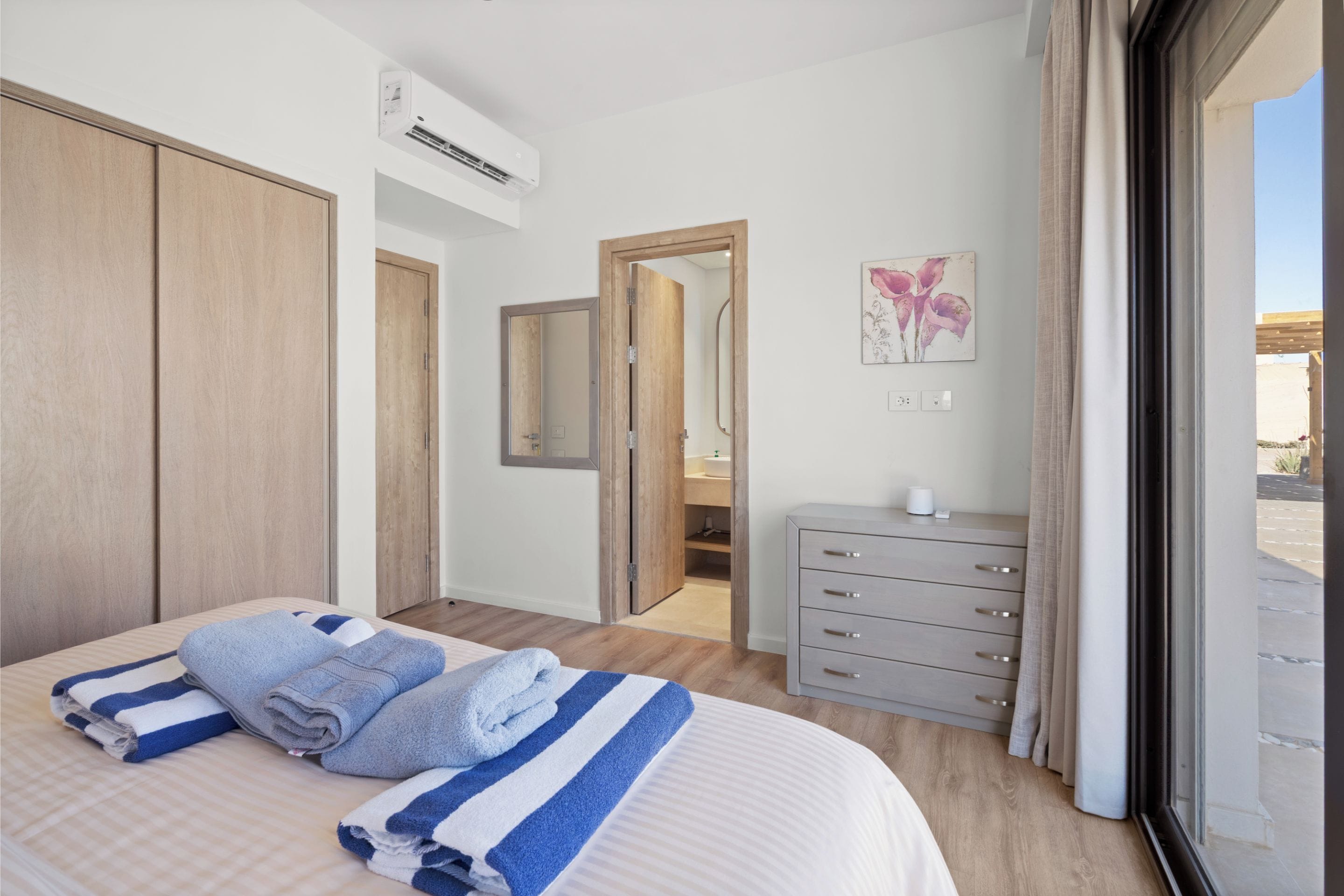 A hotel room with a bed, a dresser, a mirror, and a window.