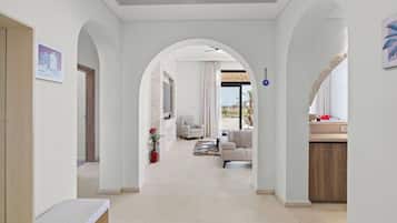 Un interior moderno con un pasillo que conduce a una sala de estar, que incluye una pared de piedra, un sofá y un comedor.