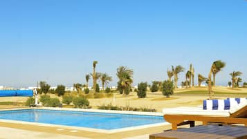 Una piscina con vistas a palmeras y un campo de golf al fondo.