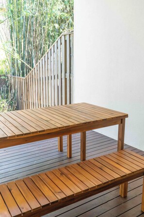 Een houten terras met een tafel en een bank.