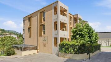 Un immeuble à plusieurs étages, doté d’une façade beige, de balcons et d’une enseigne indiquant qu’il s’agit d’un complexe résidentiel.