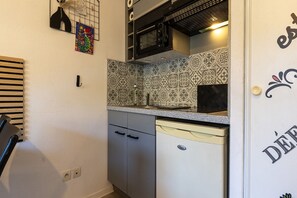 Une cuisine compacte équipée d’un four à micro-ondes, d’un lave-vaisselle et d’un crédence carrelée.