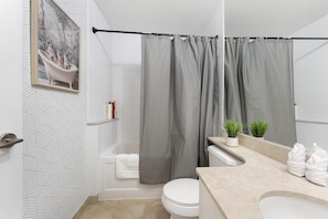 Un baño con cortina de ducha, inodoro, bañera y lavabo con espejo.