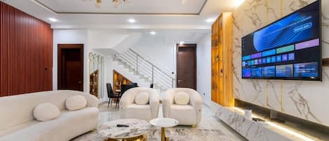 Una sala de estar moderna con un conjunto de sofá, una mesa de centro y un televisor montado en la pared.