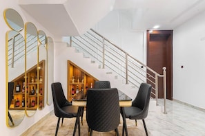 Un comedor con una mesa, sillas, una vinoteca y una escalera.