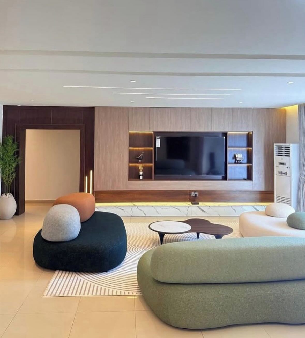 Uma sala de estar moderna com uma grande televisão de tela plana, assentos confortáveis e design minimalista.