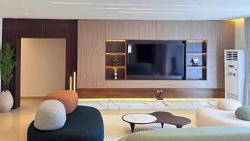 Uma sala de estar moderna com uma grande televisão de tela plana, assentos confortáveis e design minimalista.