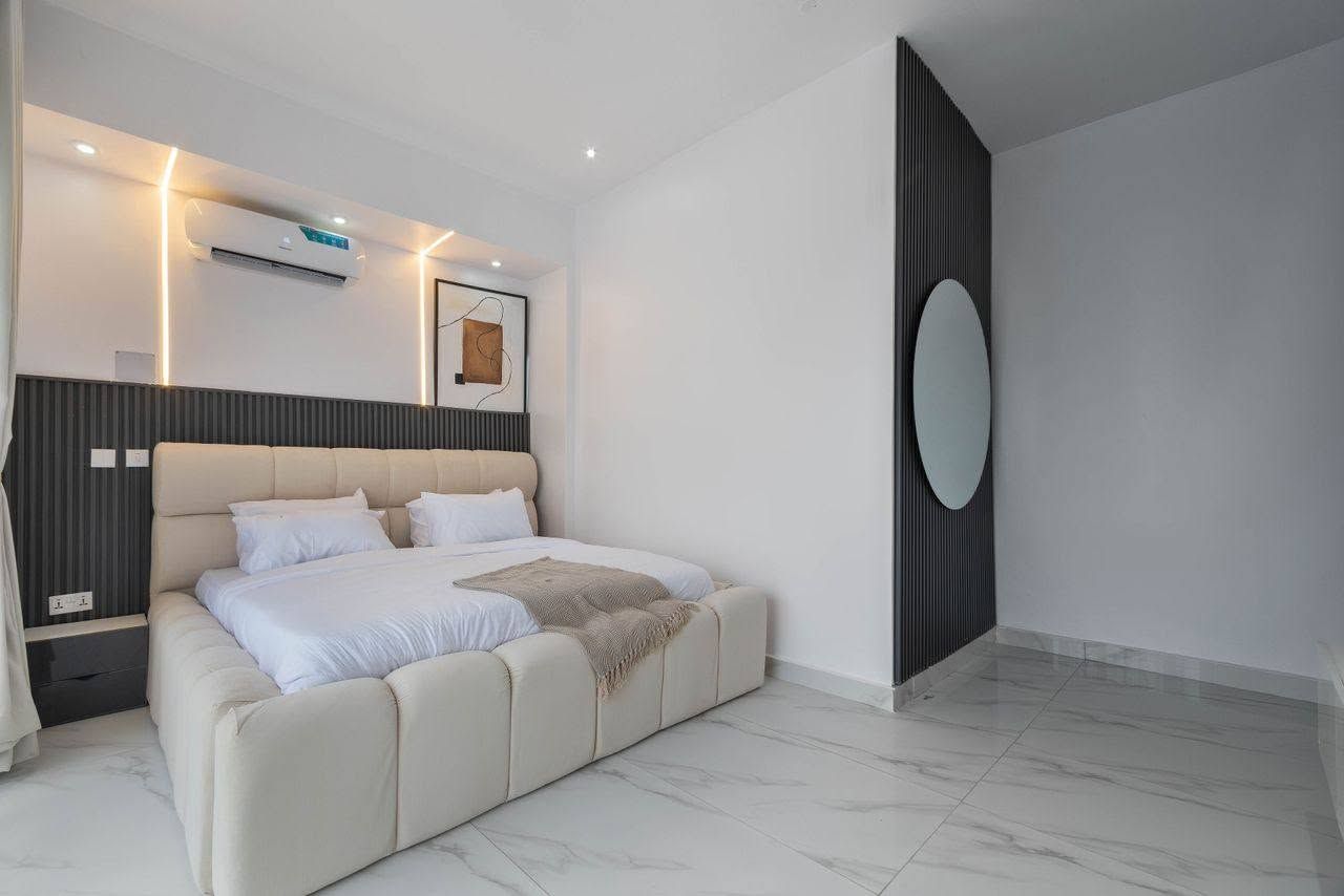 Quarto moderno com cama grande, ar condicionado na parede e um espelho amplo.