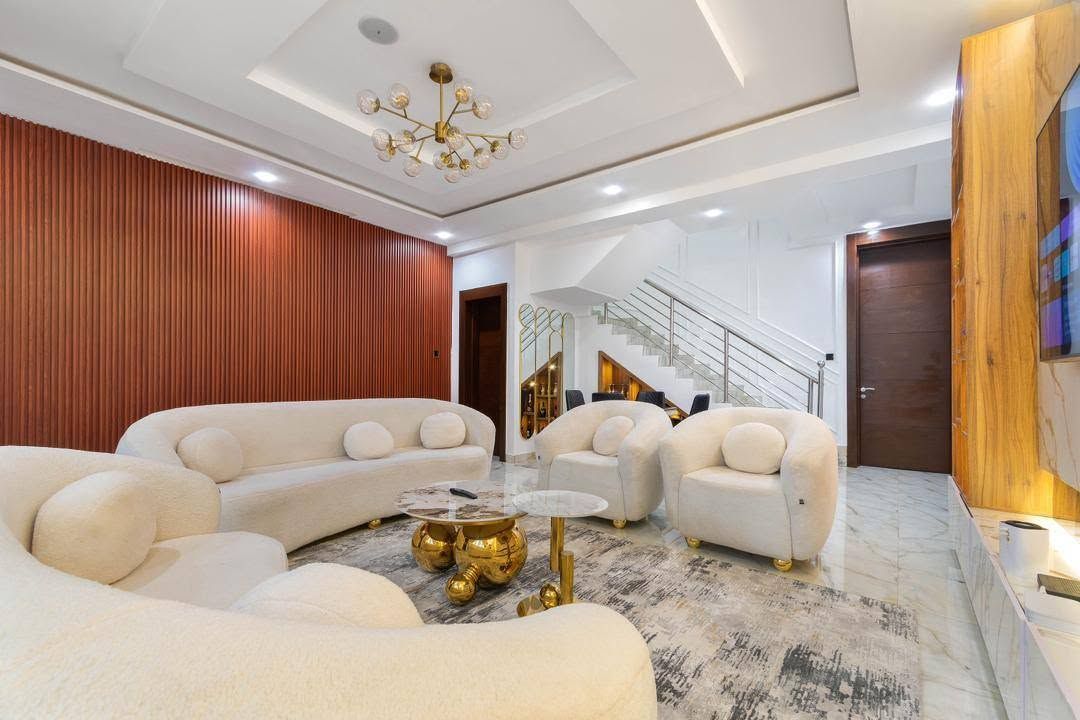 Uma sala de estar moderna com sofá seccional, mesa de centro e escada para um andar superior.