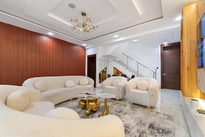 A modern living room with a sectional sofa, a coffee table, and a staircase leading to an upper level. - ORHUE APARTMENT (Benin City)