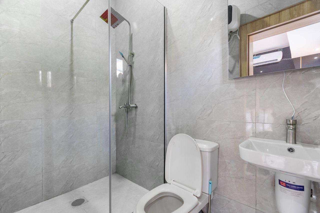 A bathroom with a glass-enclosed shower, a toilet, and a sink.