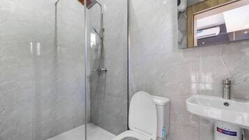 A bathroom with a glass-enclosed shower, a toilet, and a sink.