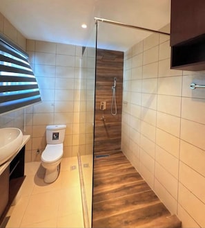Un baño moderno con ducha, inodoro y lavamanos.