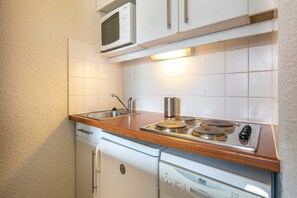 Une petite cuisine équipée d’un four à micro-ondes, d’un évier et d’une cuisinière.