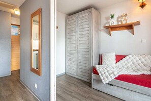 Une chambre à coucher comprenant un lit, une armoire, un miroir et une étagère avec des objets décoratifs.