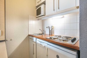 Une cuisine compacte équipée d’un four à micro-ondes, d’une cuisinière, d’un évier et d’un porte-ustensiles.