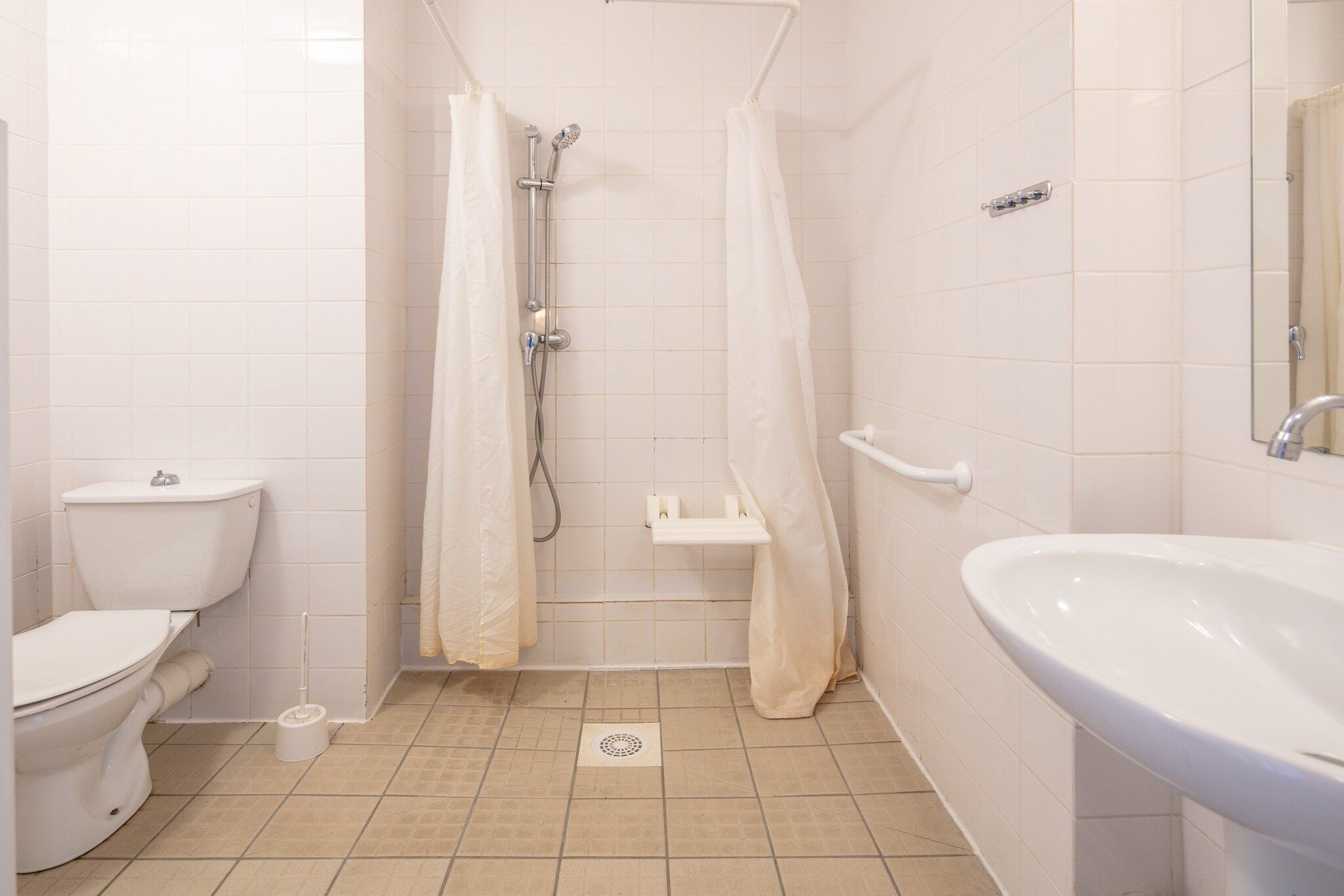 Ein Badezimmer mit Toilette, einer Duschkabine, einem Waschbecken und einem Spiegel.