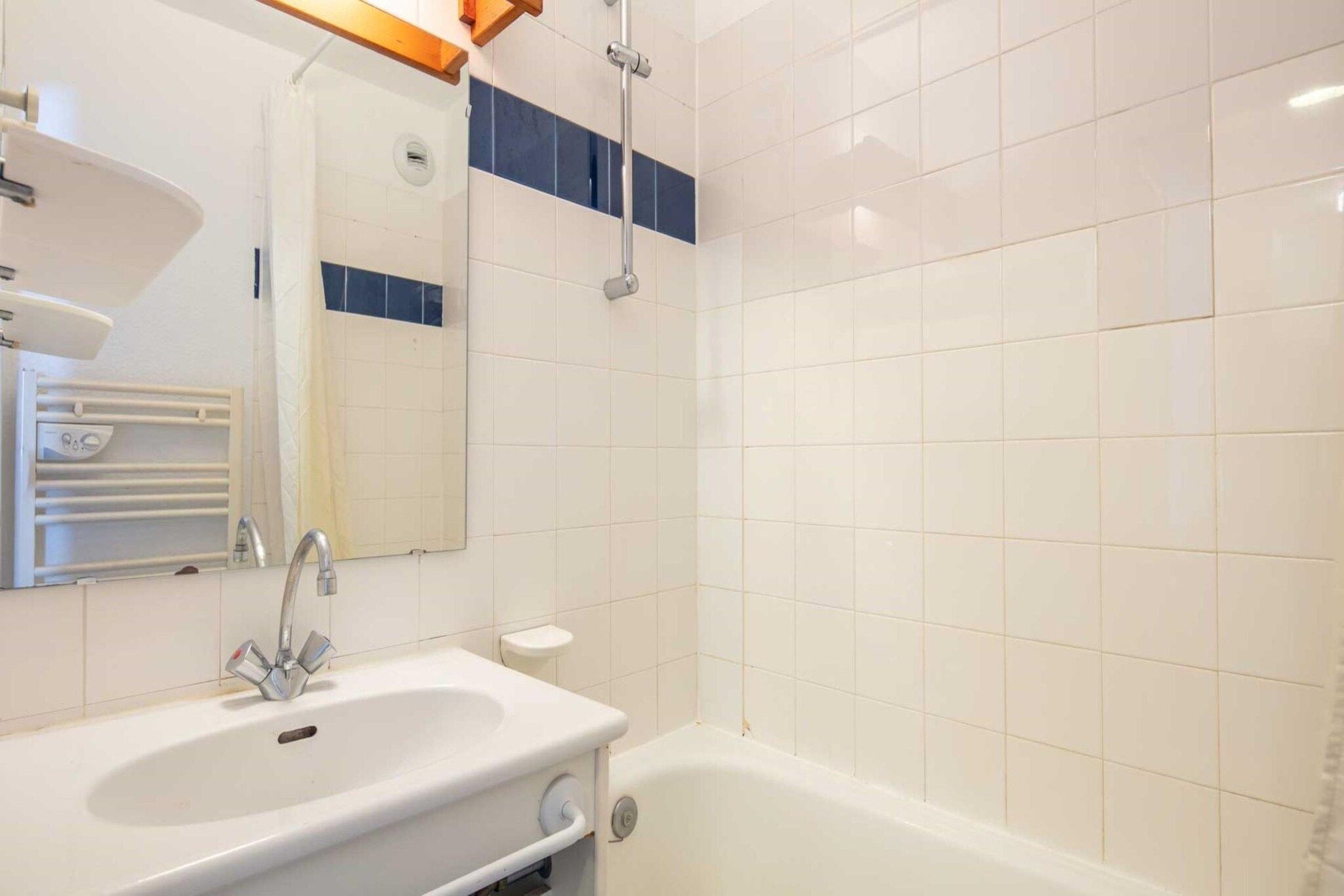 Une salle de bain avec un lavabo blanc, un miroir, une douche et des toilettes.
