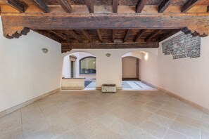A spacious attic room with a sloped ceiling, stone wall decoration, and a view through an arched doorway. - Le Charme, heart of Verona (Verona)